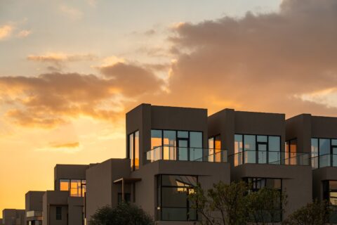 Contemporary villa community with landscaped walkways, water features, and illuminated modern villas at dusk